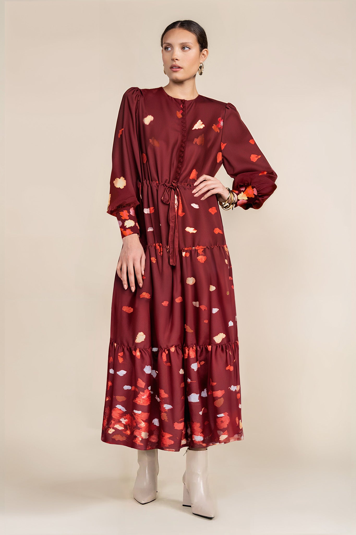 A model wearing a burgundy maxi dress with a floral pattern, featuring a drawstring waist, nursing-friendly design, and decorative covered buttons.